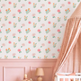 Girls nursery with pink floral stripe wallpaper crib gingham canopy and blush wall paneling.