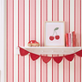 Scalloped stripe wallpaper with red bunting and shelf decor, pink striped kids room wallpaper styling