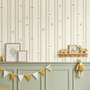 “Wallpaper backdrop with wooden wall shelf displaying framed animal prints, wooden toys, and soft plush decor.”