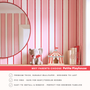Pink red stripe wallpaper behind nursery shelf styling with toys and mirror, playful kids room wall decor