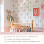 Baby nursery wall with floral stripe wallpaper above wall molding wooden shelf books and scalloped lamp.