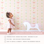 Toddler girl in pink dress standing against bow floral wallpaper, pastel nursery wall decor with rocking horse, soft baby girl room