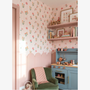Children's play kitchen with floral wallpaper and a green chair.