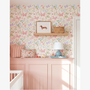 Butterfly floral wallpaper behind nursery shelf styling with cushions, lamp and toys, pastel girls bedroom wall decor