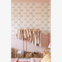 Children’s clothing rack styled nursery with floral stripe wallpaper pink wall paneling and woven storage baskets.
