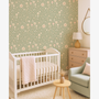 Neutral sage green nursery with woodland mushroom wallpaper, baby crib, armchair and soft natural decor