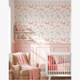 Pastel butterfly wallpaper above blush pink wall panelling, baby girl nursery with crib and armchair, soft floral nursery decor