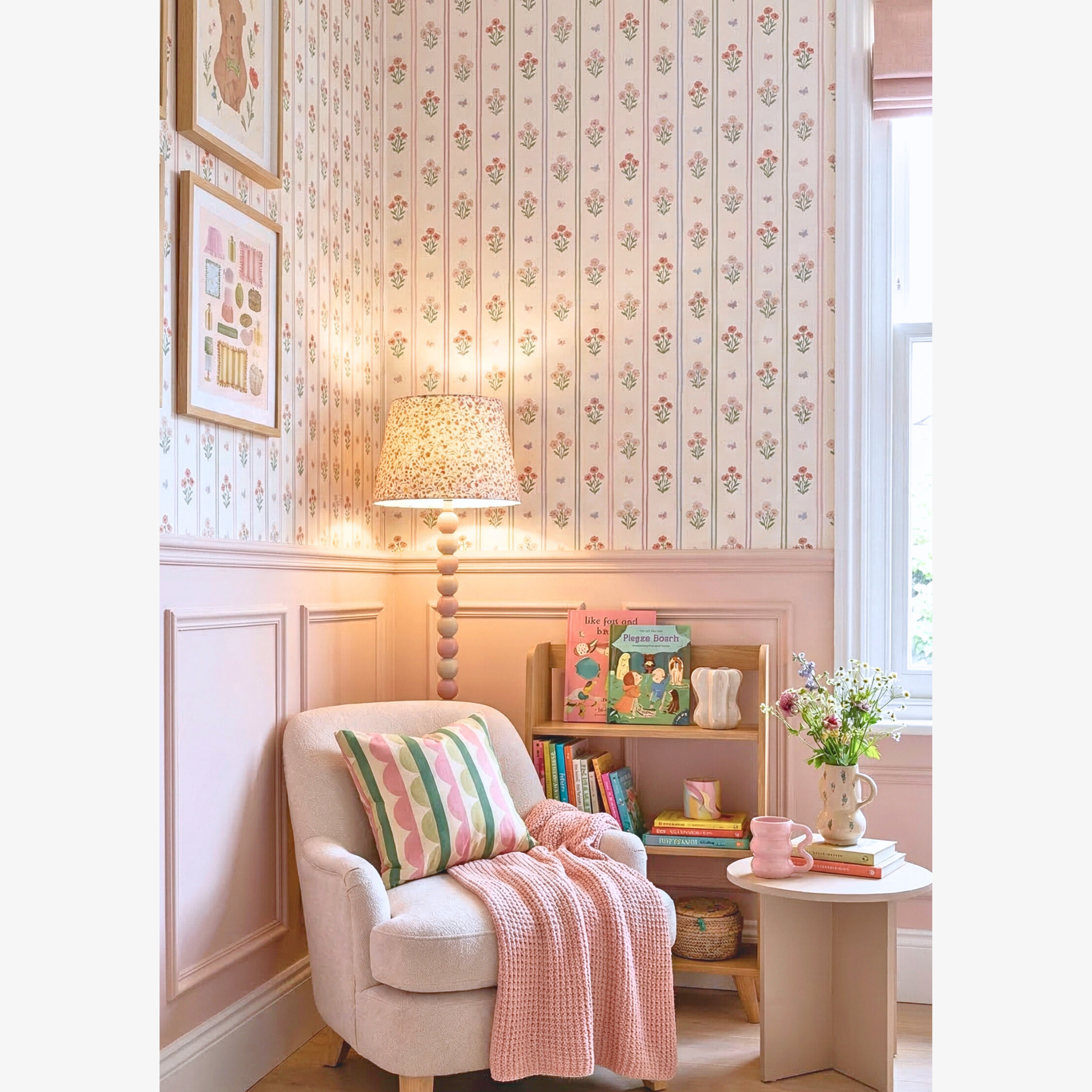 Cozy nursery reading corner with floral stripe wallpaper armchair pastel cushion wooden bookshelf and children's books.
