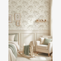 Children's room with wallpaper featuring small houses, rocking chair, and armchair.
