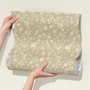 Roll of beige wallpaper with floral pattern held by a person