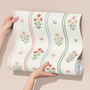 Roll of floral wallpaper held by a person on a beige background